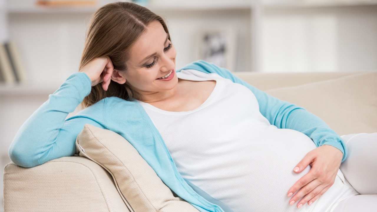 Happy pregnant woman lying on couch